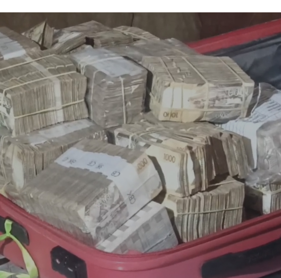 Bundles of banknotes packed into a red suitcase
