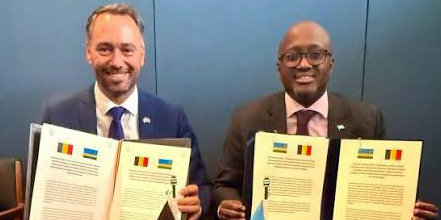 Rwandan and Belgian officials holding signed documents in front of their national flags