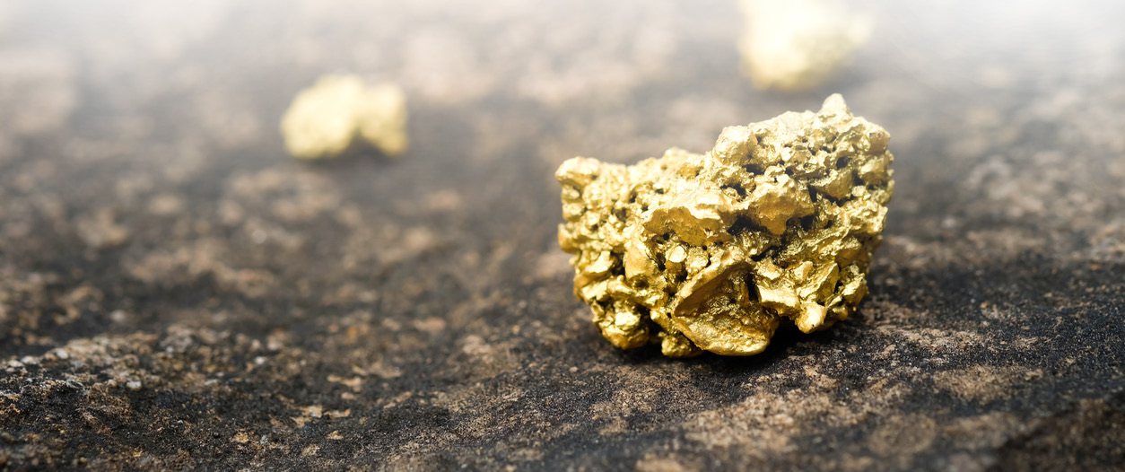 Raw gold nuggets on a dark surface